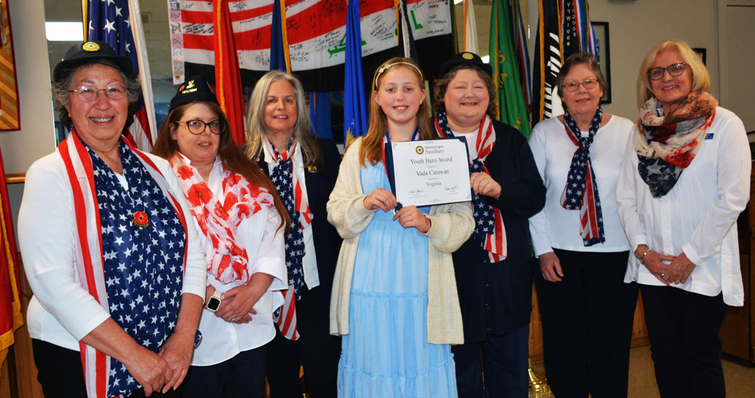 American Legion Auxiliary, Virginia Department, awarded the 'Youth Hero Award' to Vada Carawan on March 26, 2025 in Virginia Beach, VA.  Making the presentation of a certificate and medal was Tonya Jones, President of the American Legion Auxiliary Unit 110.  Vada Carawan was sited for her quick action when her father was having a health emergency.  She applied CPR chest compressions to her dad while on the phone with the 911 dispatcher.  With the help of paramedics, who quickly arrived, her dad's heart was beating again.  What's incredible is that 11 days prior to this incident, she had learned CPR procedures at her Girl Scout meeting.  In the photograph (l to r) are Jesse Basso, Cyndi Fisher, Debbie Castrinos, Vada Carawan, Tonya Jones, Dale Smith and Mary Kinkin.  (Photography by Bert Wendell, Jr.)